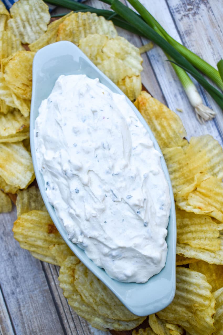 copycat dean's french onion dip in a small gray serving bowl surrounded by potato chips