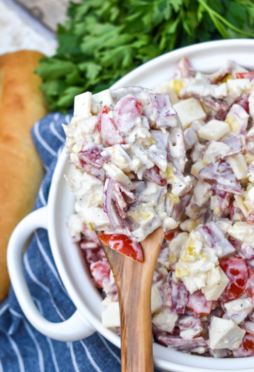 a wooden spoon holding up a scoop of Italian grinder chicken salad