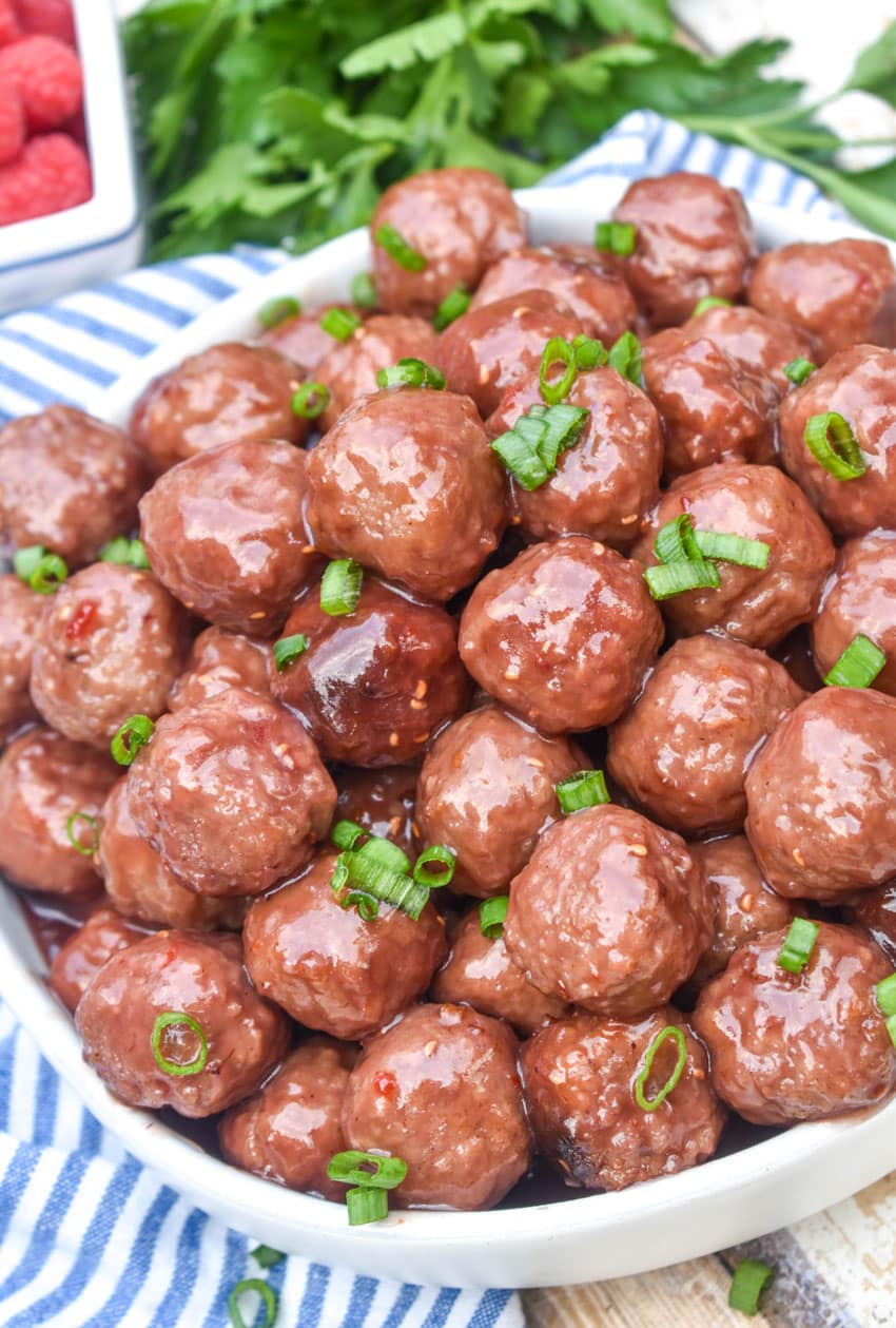 the best party meatballs piled high in a white serving bowl
