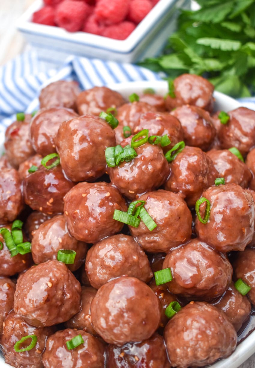 the best party slow cooker meatballs piled high in a white serving bowl