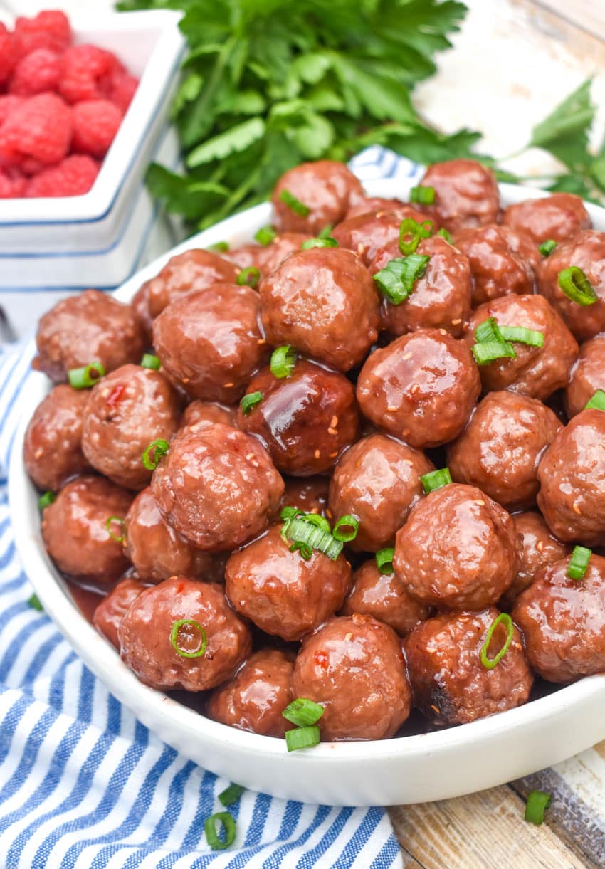 the best party crockpot meatballs piled high in a white serving bowl