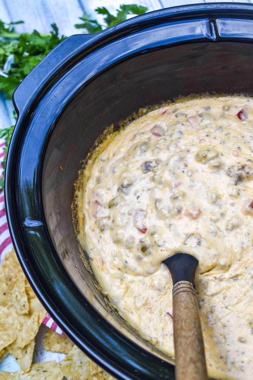 extra creamy queso dip in the black crock of a slow cooker