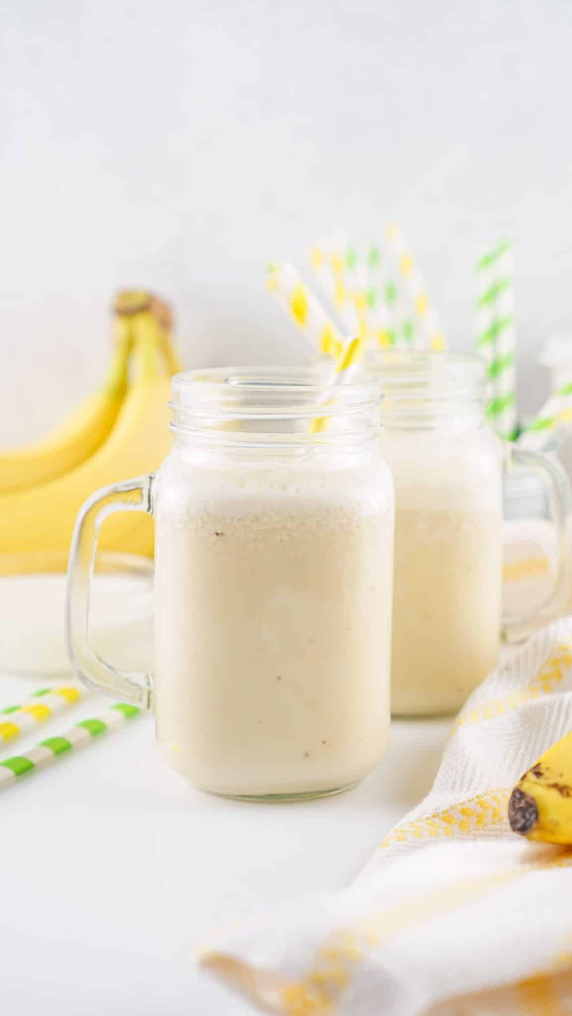 banana milk in two glass jars with paper straws in them