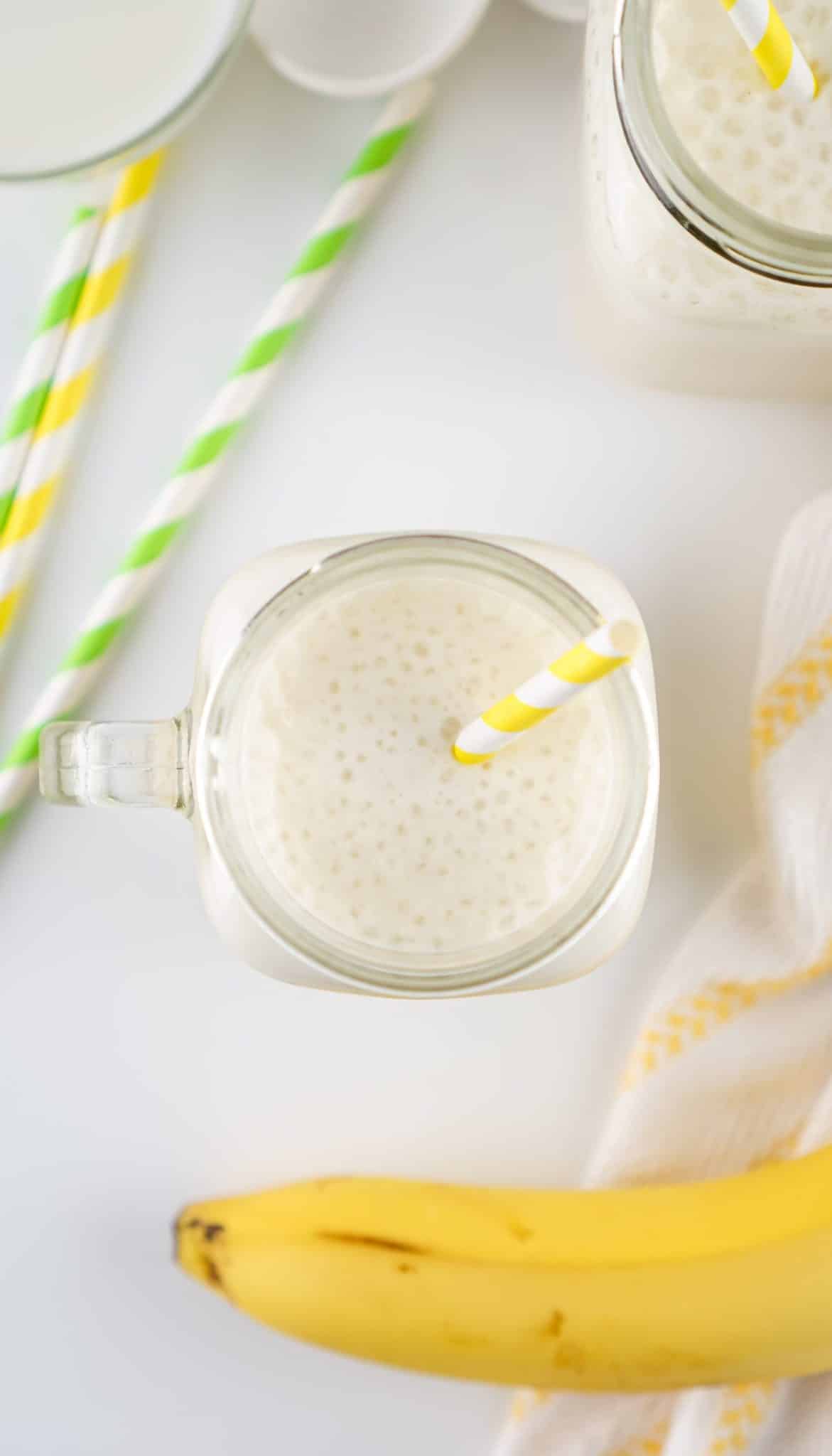 an overhead image showing banana milk in a glass jar