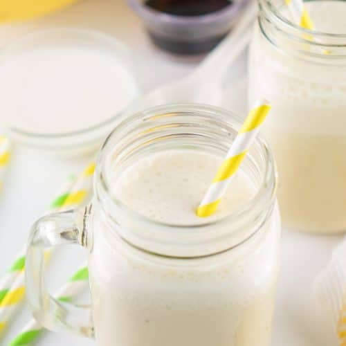 banana milk in two glass jars with paper straws in them