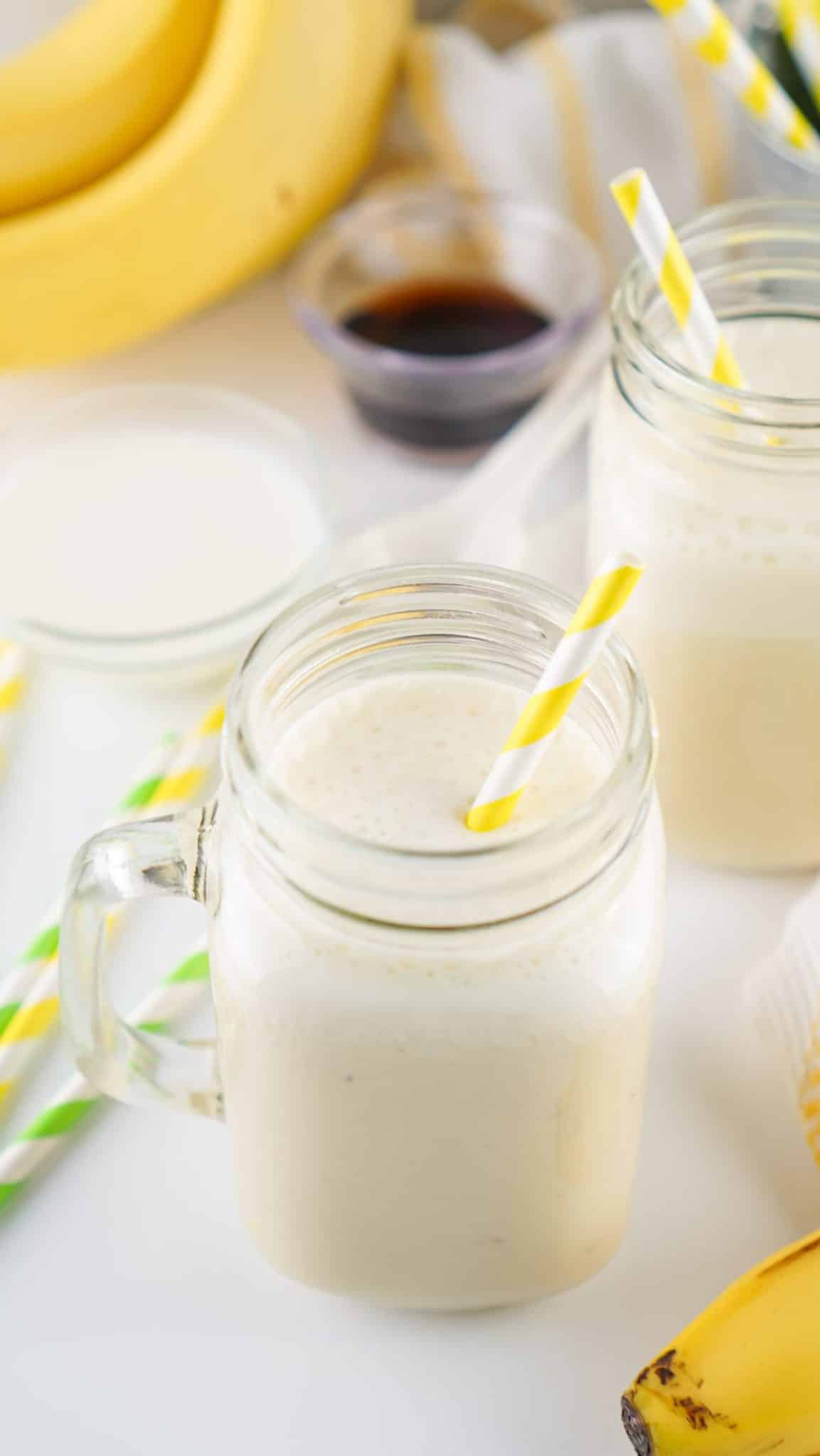 banana milk in two glass jars with paper straws in them