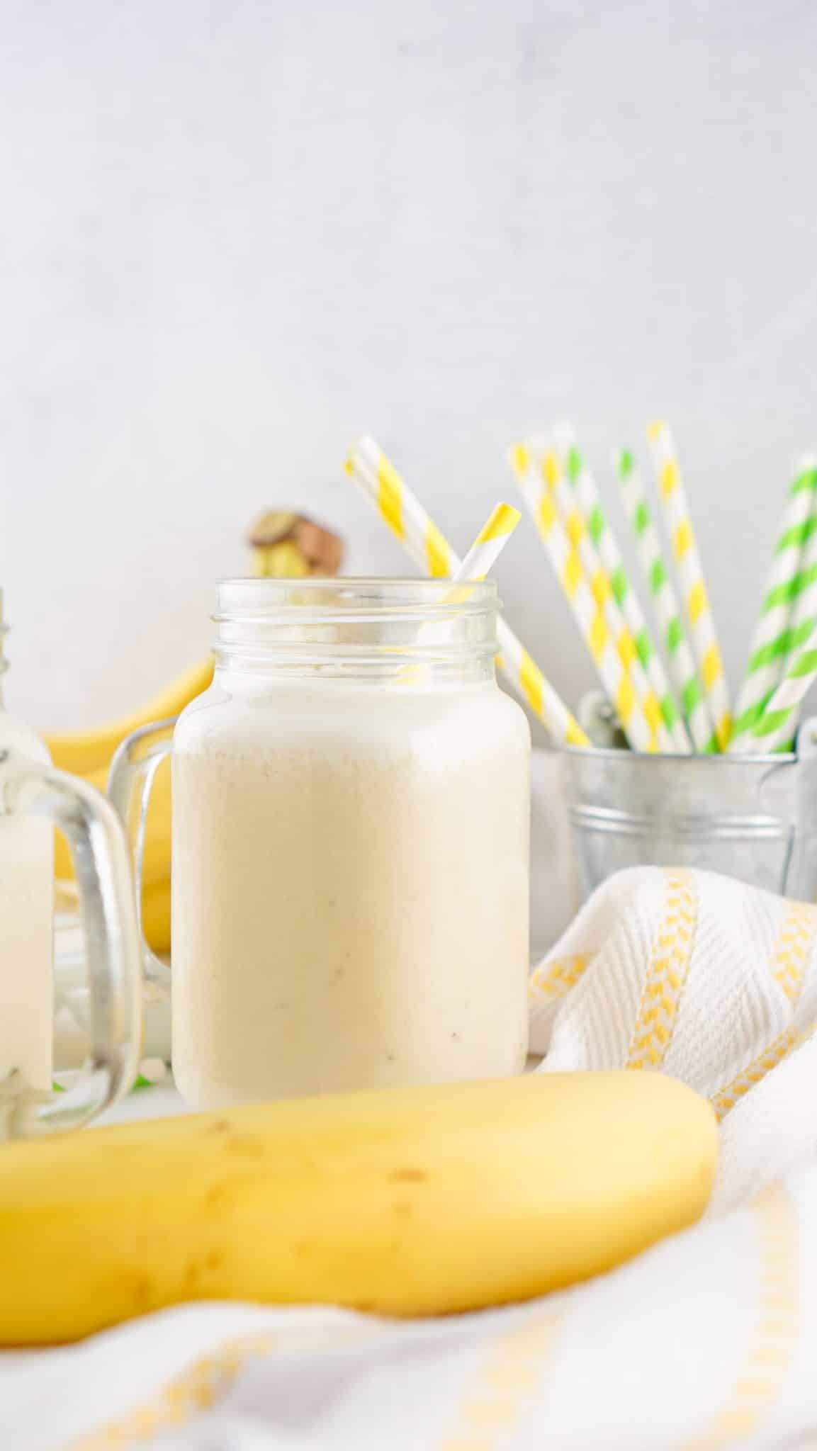 banana milk in a glass jar with paper straws in the background