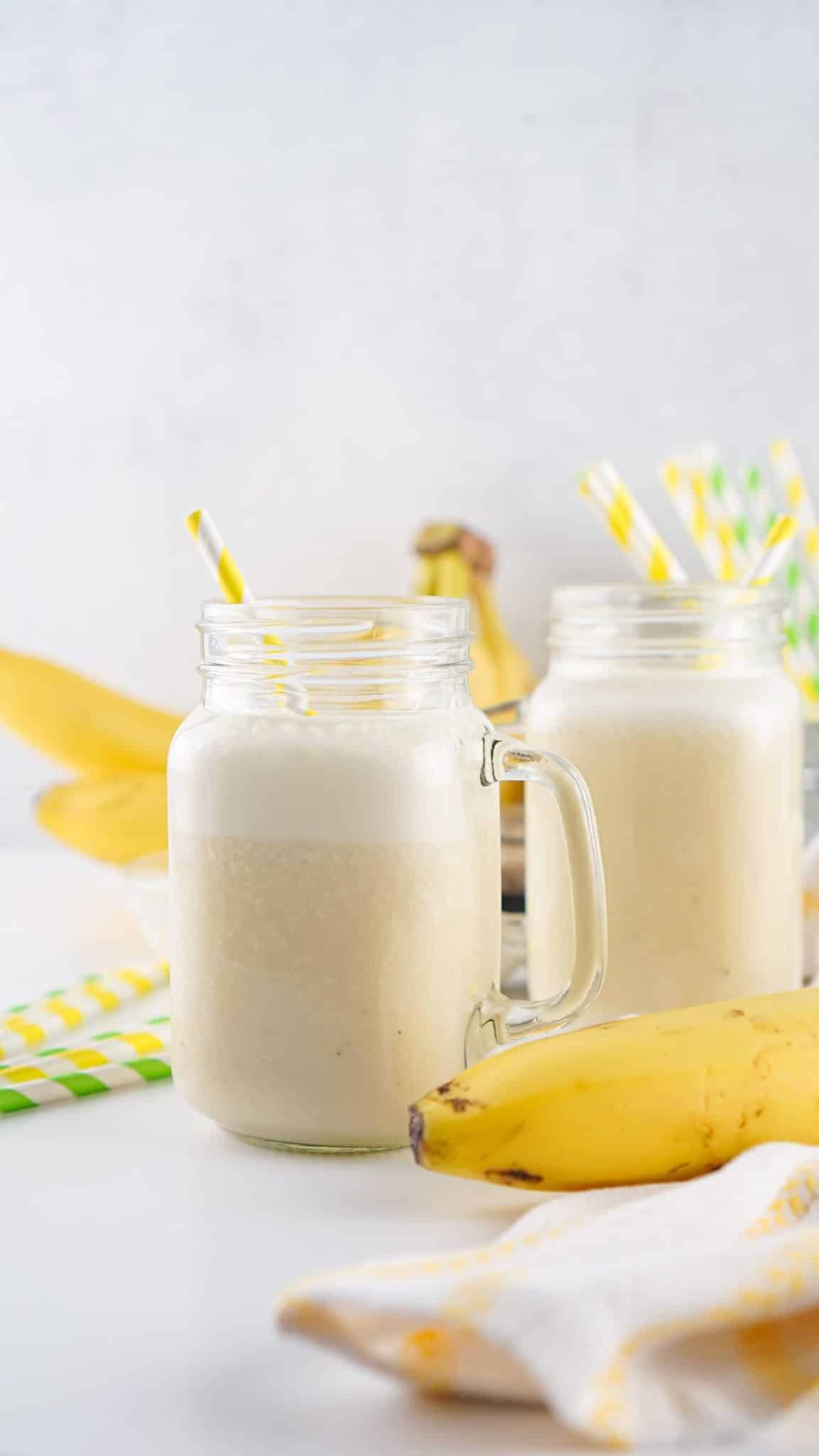 banana milk in two glass jars with paper straws in them