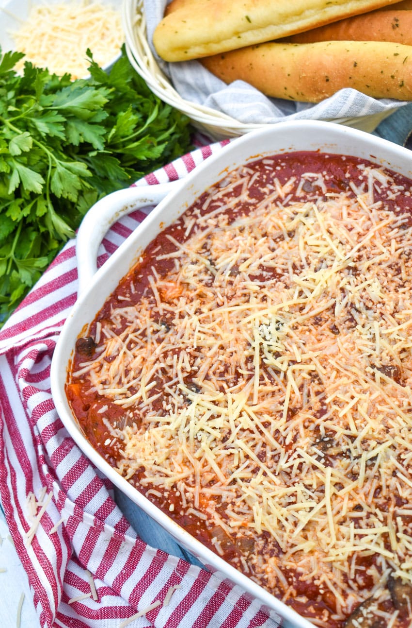 italian pierogi bake in a white casserole dish topped with melted shredded parmesan cheese
