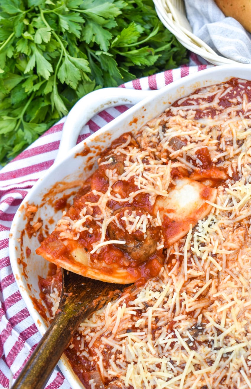 a wooden spatula scooping an italian pierogi bake out of a white casserole dish