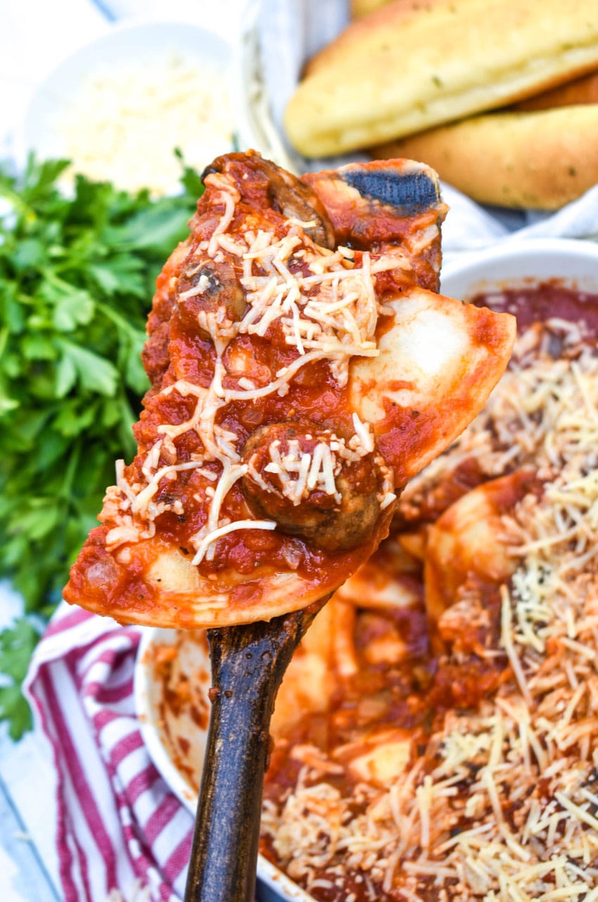 a wooden spatula holding up a scoop of a dump and bake italian pierogi casserole