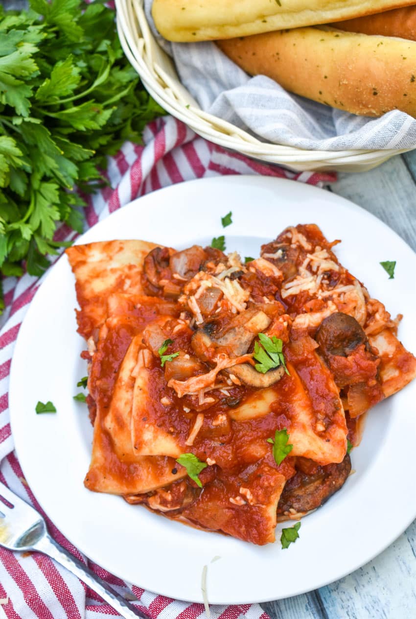 dump and bake italian pierogi bake on white plate with fresh herbs sprinkled on top