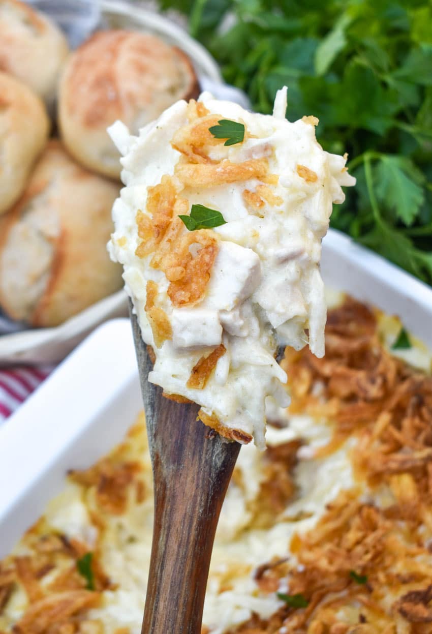 a wooden spoon holding up a scoop of french onion chicken casserole