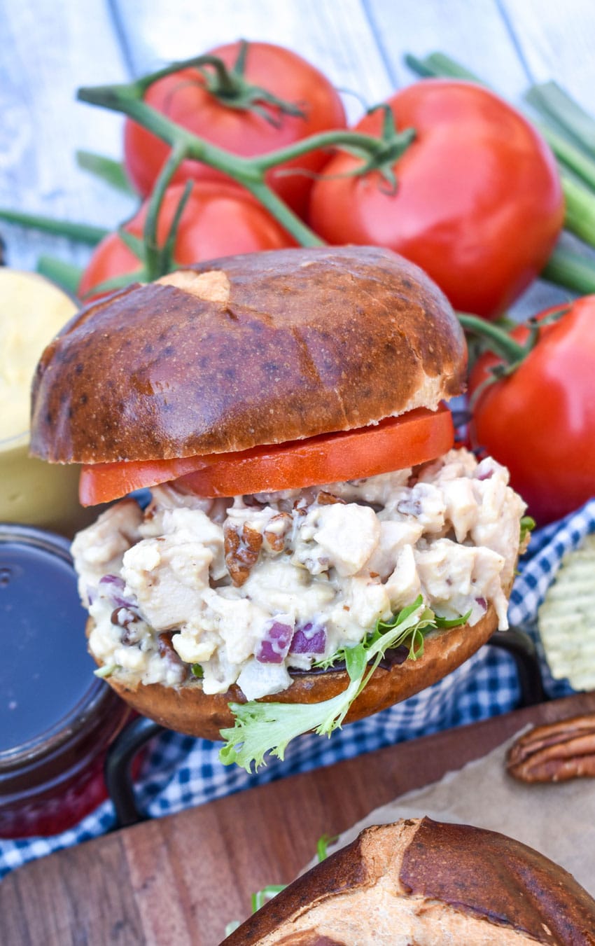 honey mustard chicken salad sandwich on pretzel buns on a wooden cutting board