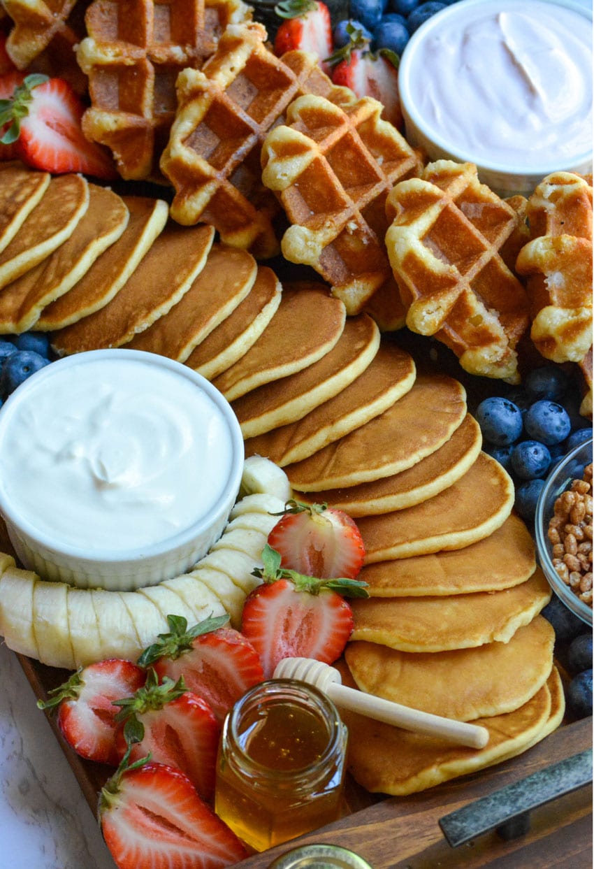 an overhead image of a pancake and waffle breakfast board spread