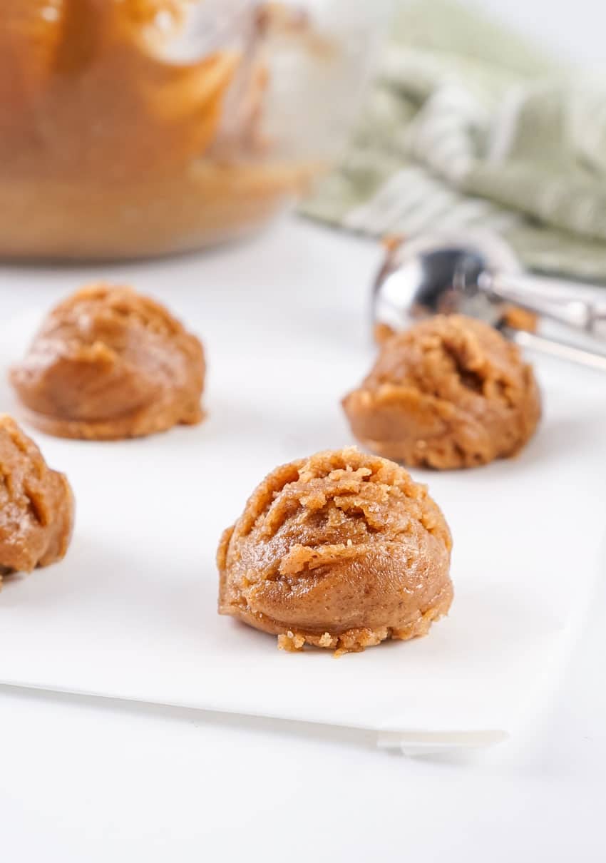 four dollops of almond butter cookie dough on a white piece of parchment paper