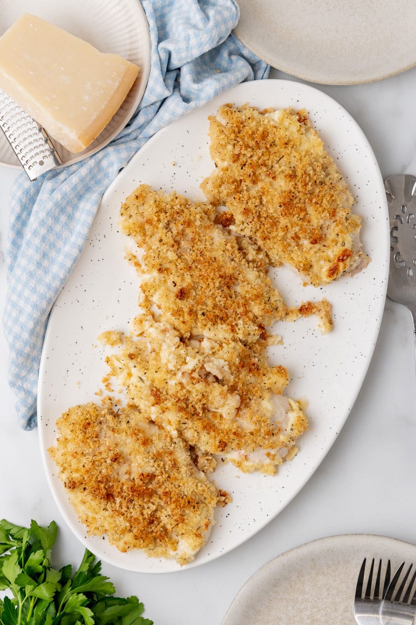 longhorn copycat parmesan crusted chicken breasts in a row on a white serving platter