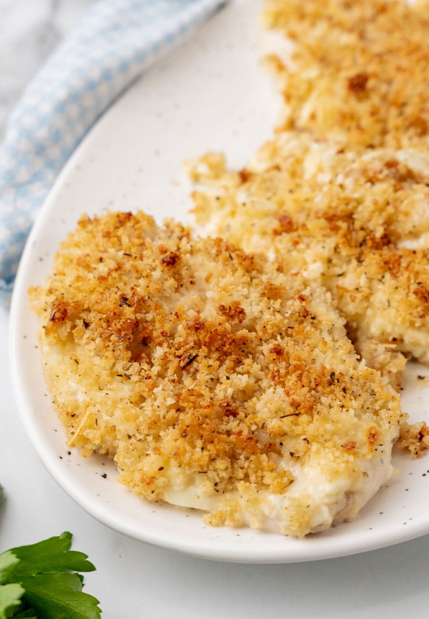 longhorn copycat parmesan crusted chicken breasts in a row on a white serving platter