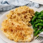 LONGHORN STEAKHOUSE'S PARMESAN CRUSTED CHICKEN ON A WHITE DINNER PLATE WITH BROWN RICE AND GREEN BEANS ON THE SIDE