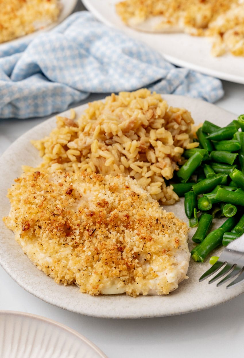 LONGHORN STEAKHOUSE'S PARMESAN CRUSTED CHICKEN ON A WHITE DINNER PLATE WITH BROWN RICE AND GREEN BEANS ON THE SIDE