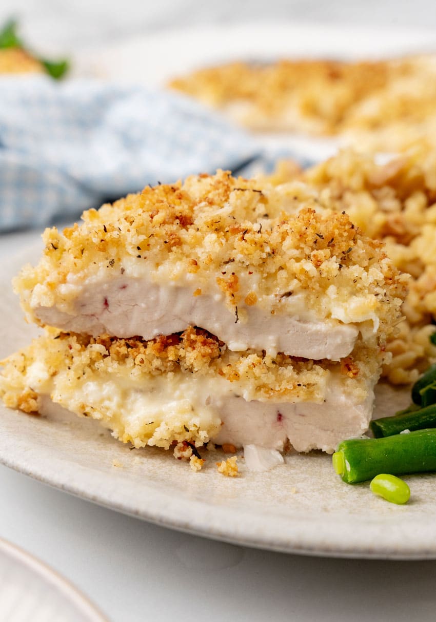 two slices of parmesan crusted chicken stacked together on a white dinner plate