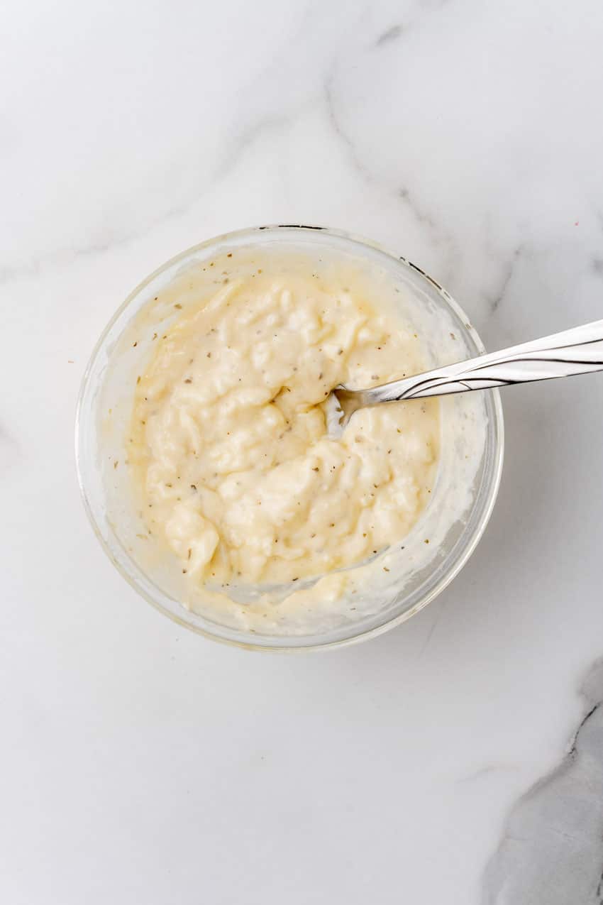 provolone and parmesan cheese in ranch dressing in a glass mixing bowl