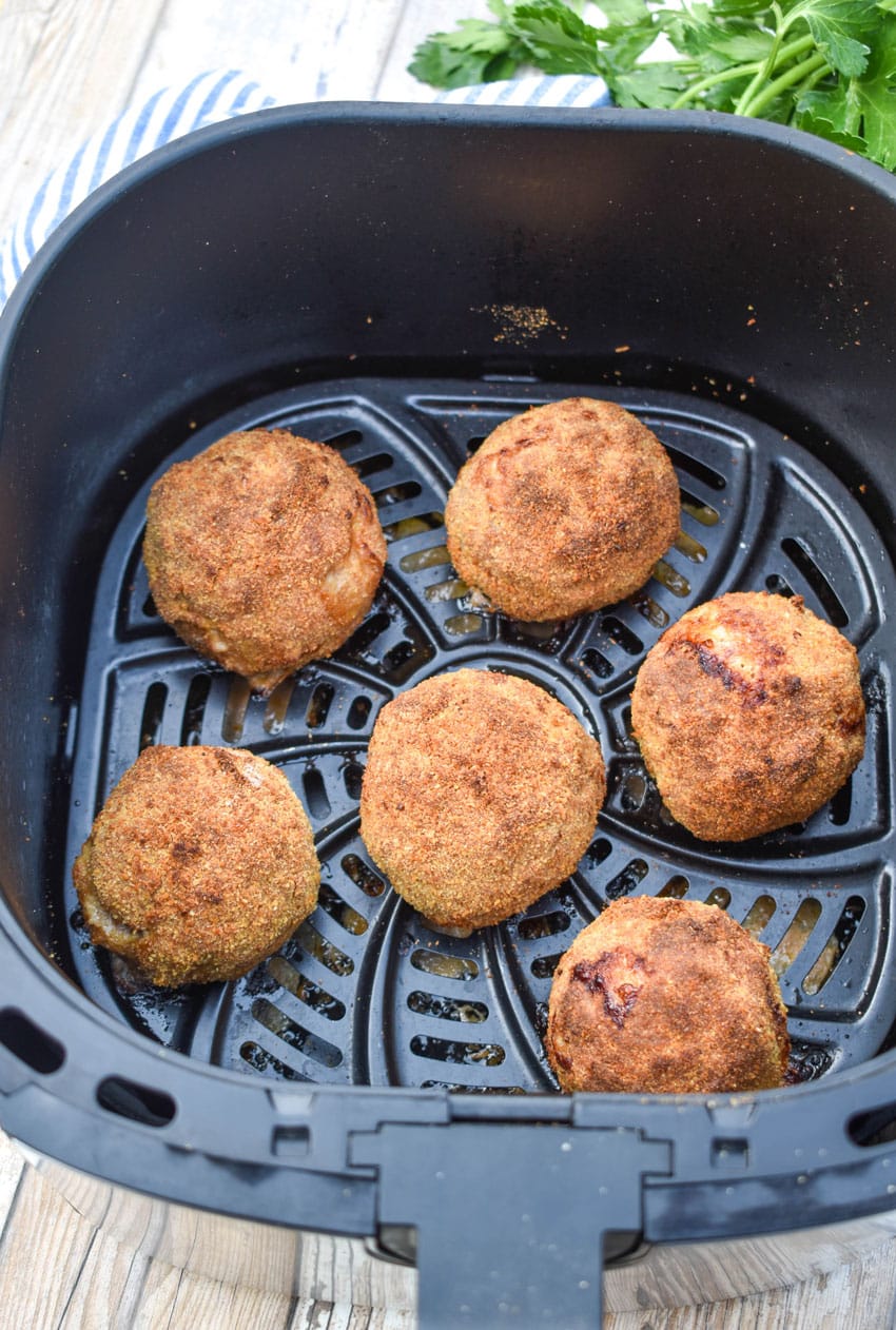 cooked sausage balls in the basket of an air fryer