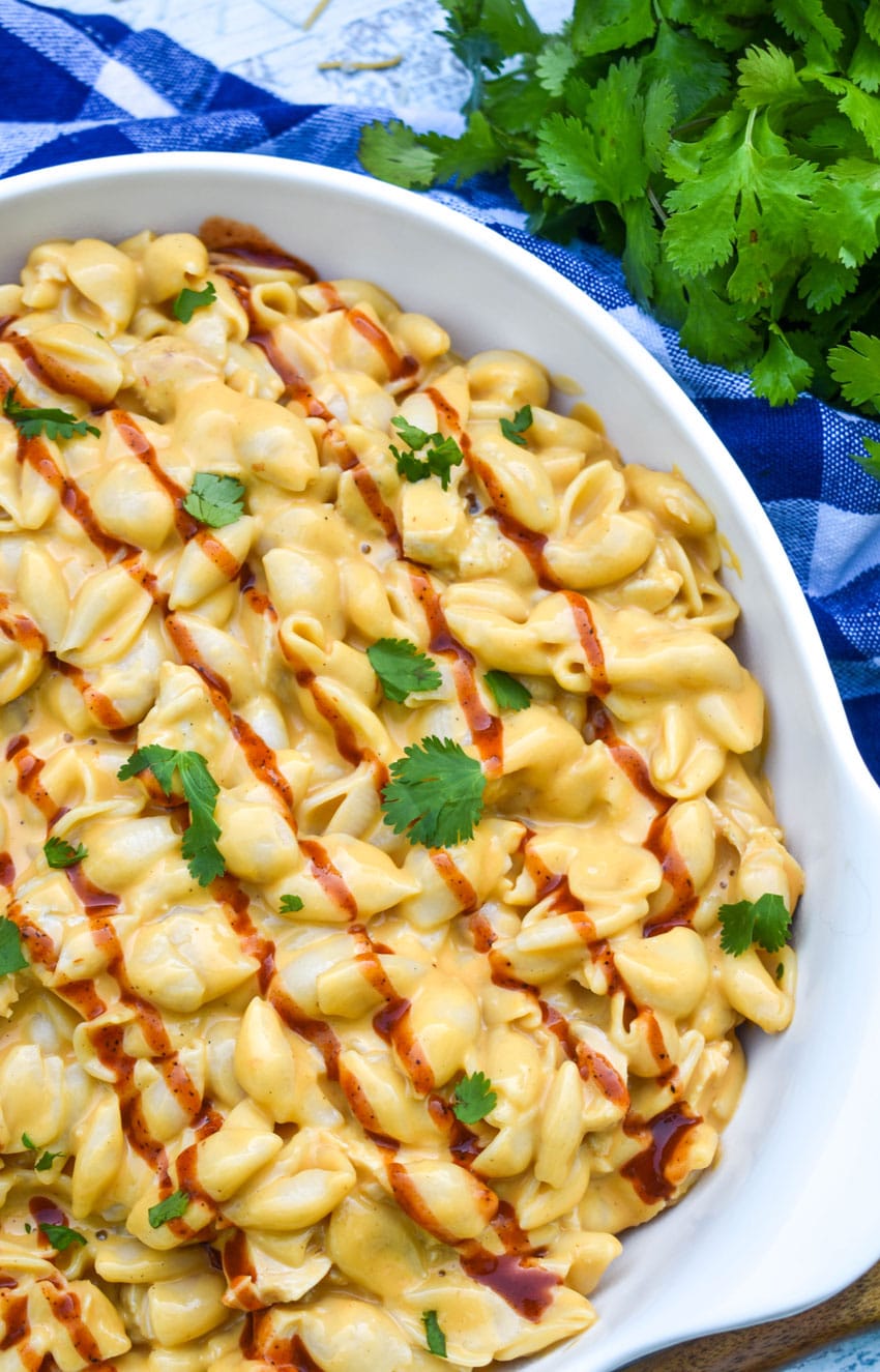 barbecue chicken mac and cheese drizzled with barbecue sauce in a white serving bowl