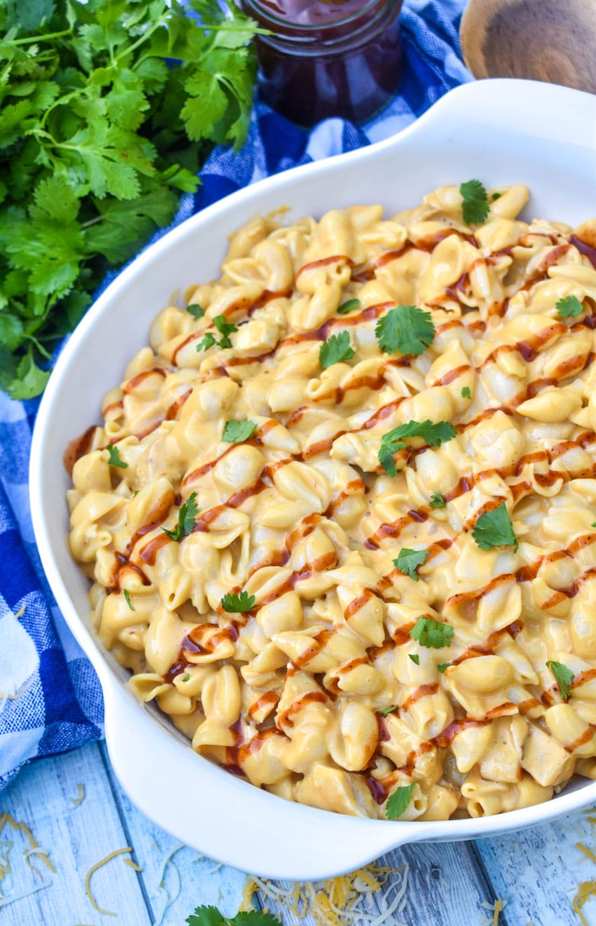 barbecue chicken mac and cheese drizzled with barbecue sauce in a white serving bowl