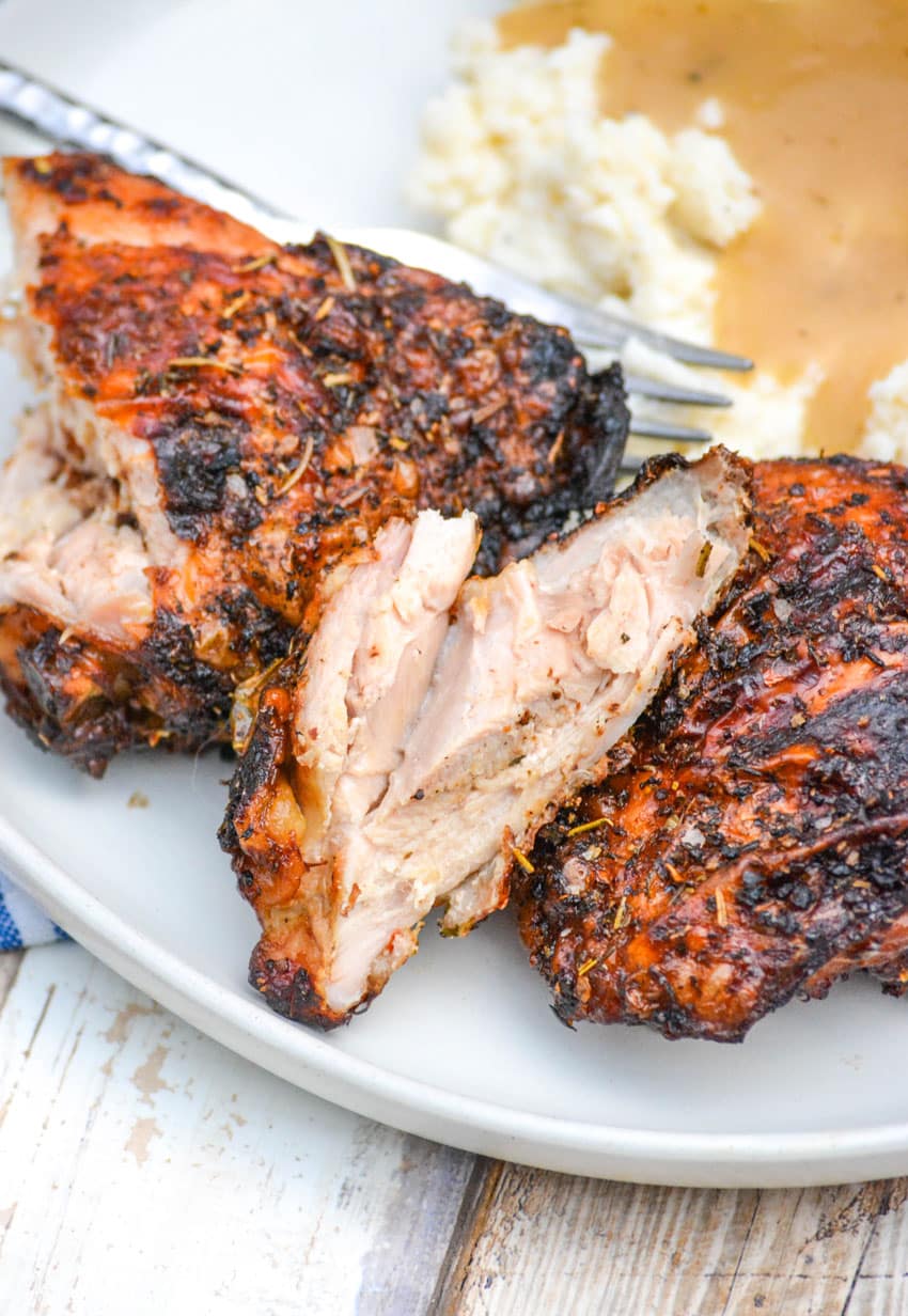 air fried crispy chicken thighs on a white plate with mashed potatoes and gravy on the side