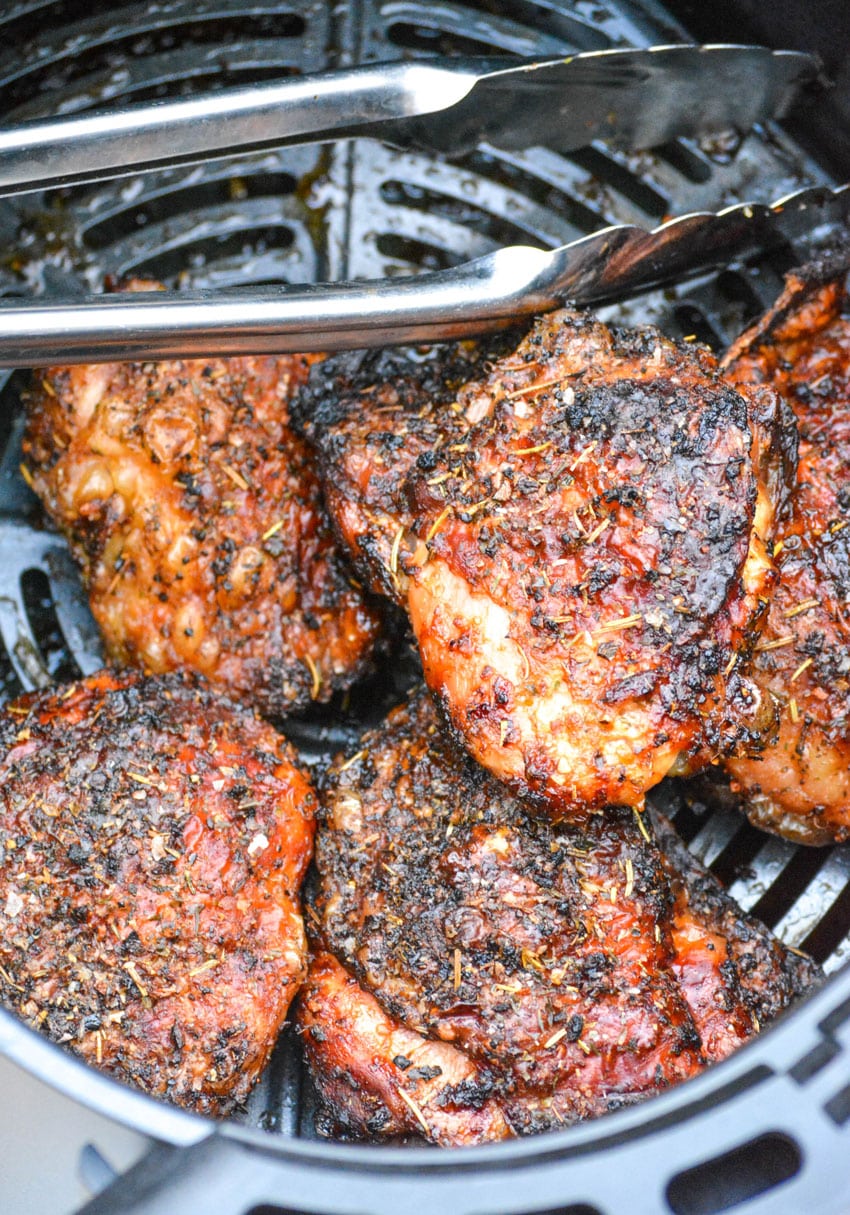 crispy chicken thighs in the basket of an air fryer
