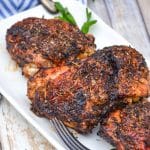 air fried crispy chicken thighs on a white serving platter with fresh herbs in the background