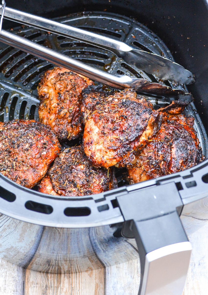 crispy chicken thighs in the basket of an air fryer