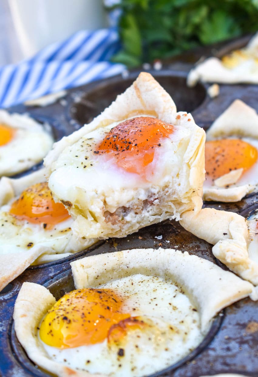 mini breakfast pie cups resting on the edge of a muffin tin pan