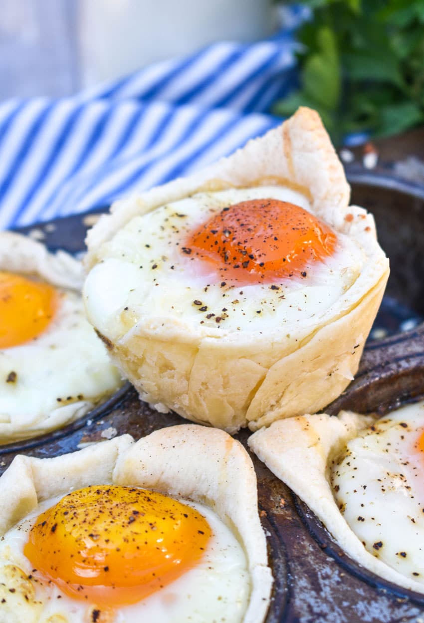 mini breakfast pie cups resting on the edge of a muffin tin pan