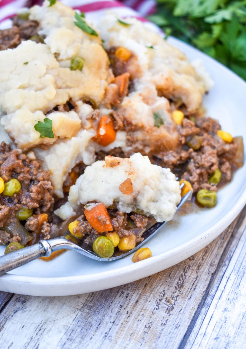 slow cooker shepherds pie served on a white dinner plate with a silver fork on the side