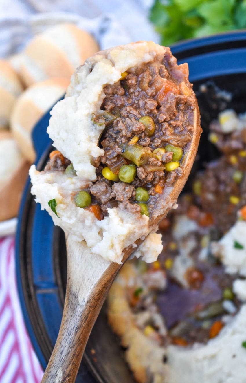 a wooden spoon holding up a scoop of slow cooker shepherd's pie