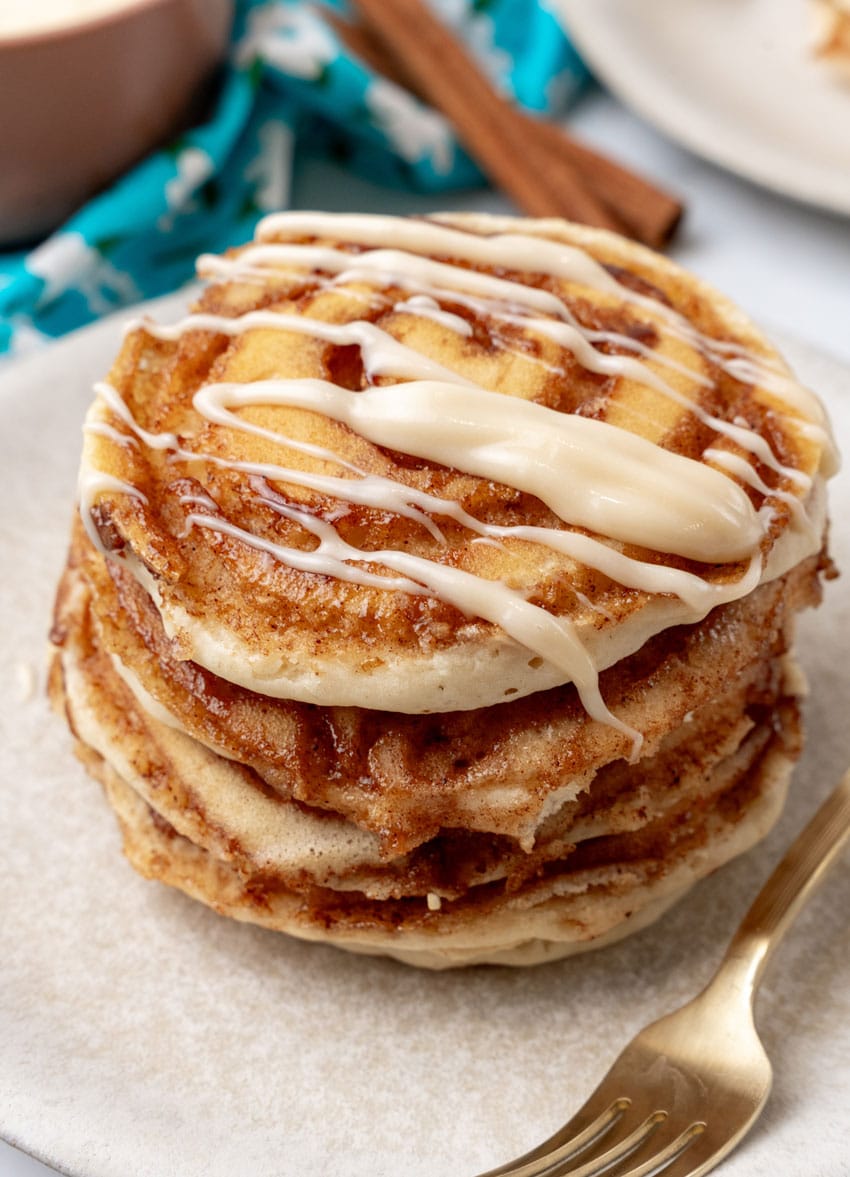 a stack of cinnamon roll pancakes on a white plate