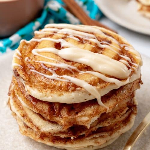 a stack of cinnamon roll pancakes on a white plate