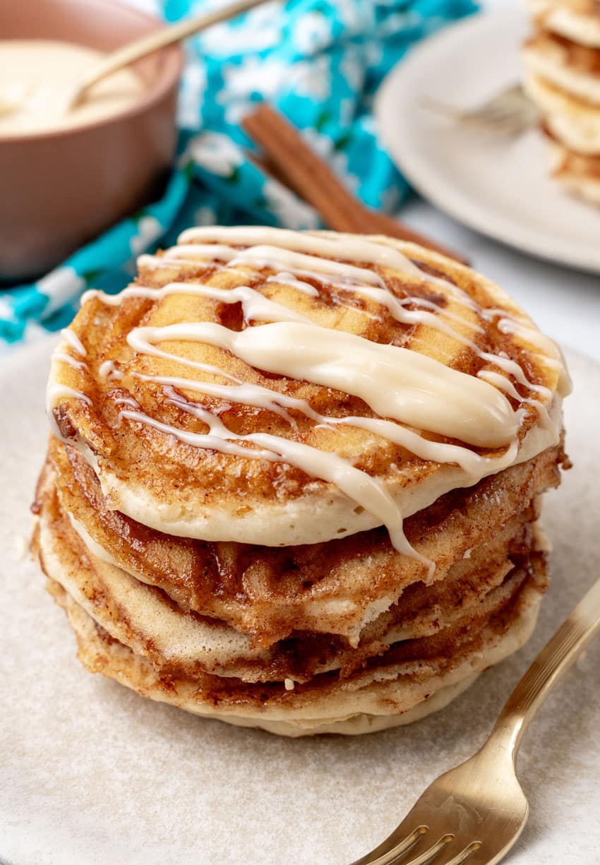 a stack of cinnamon roll pancakes on a white plate