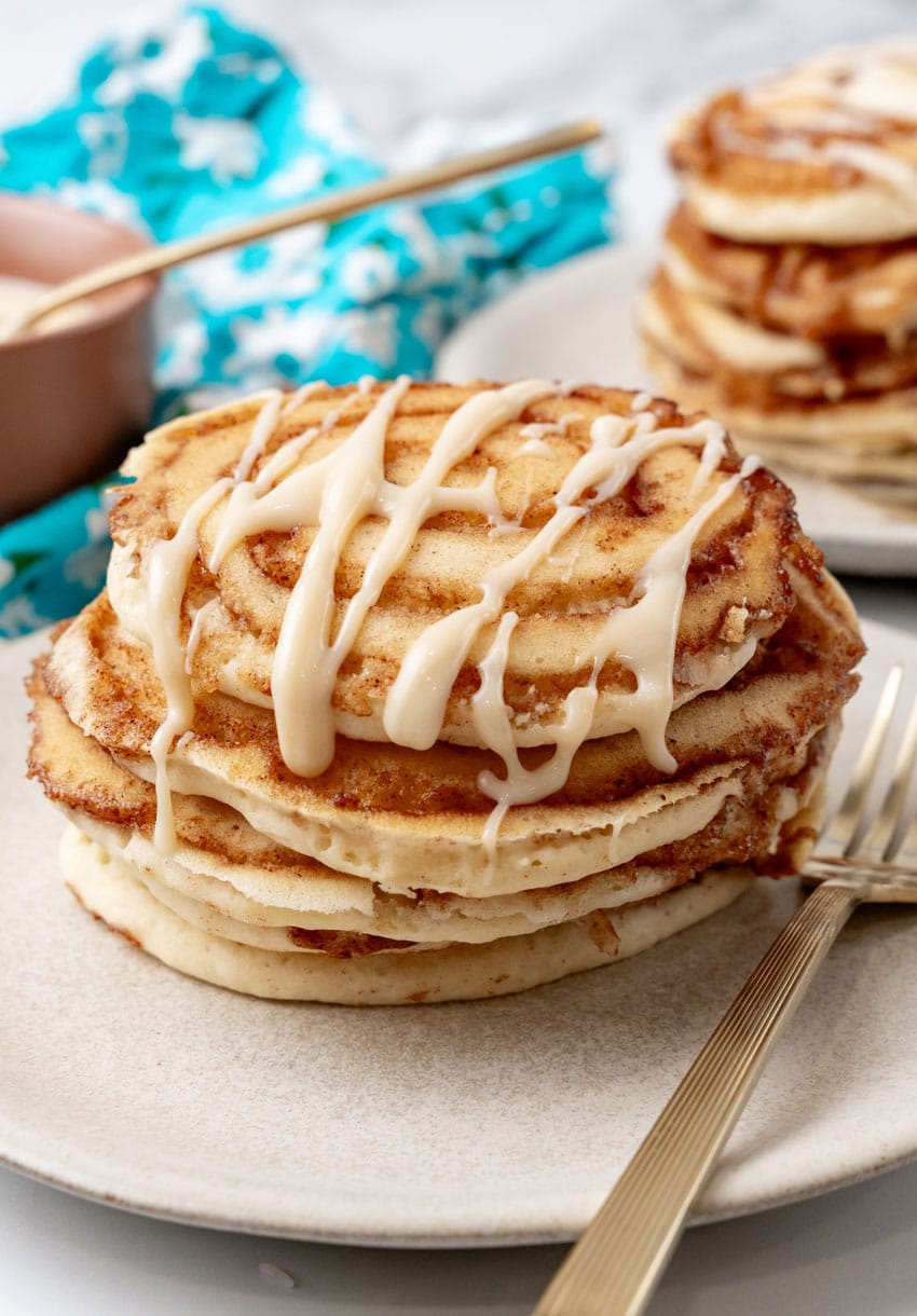 a stack of cinnamon roll pancakes on a white plate