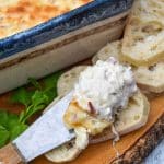 chicken cordon bleu dip on a cheese spreader resting on slices of baguette bread