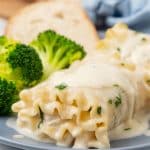 white chicken lasagna roll ups and steamed broccoli on a small blue plate