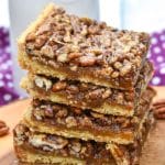 a stack of easy pecan bars on a wooden cutting board