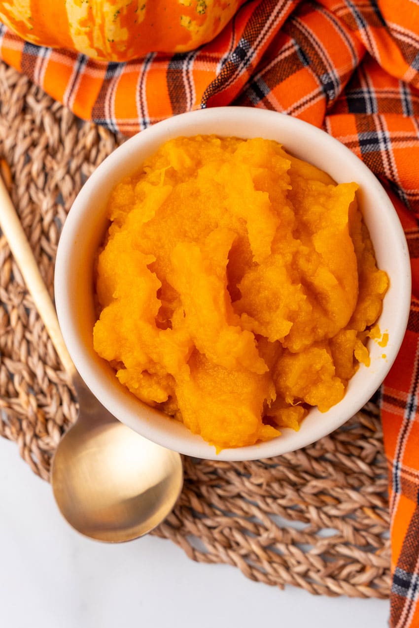 an overhead image showing homemade pumpkin puree in a small white bowl