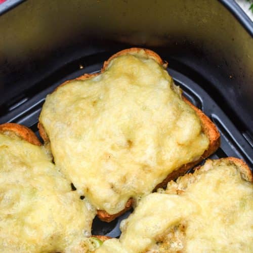 open face tuna melt sandwiches in the basket of an air fryer