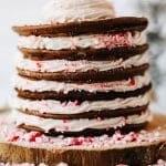 a stack of peppermint pancakes on a wooden cutting board surrounded by peppermint candy pieces