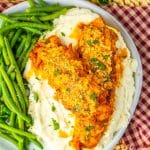 garlic parmesan baked chicken over mashed potatoes on a gray plate