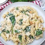 slow cooker chicken caesar pasta on a gray plate with fresh herbs in the background