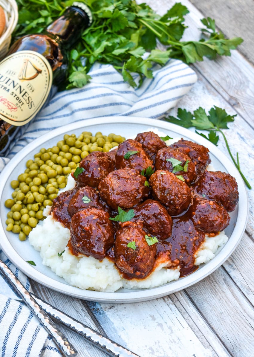 slow cooker guinness meatballs over mashed potatoes on a white plate